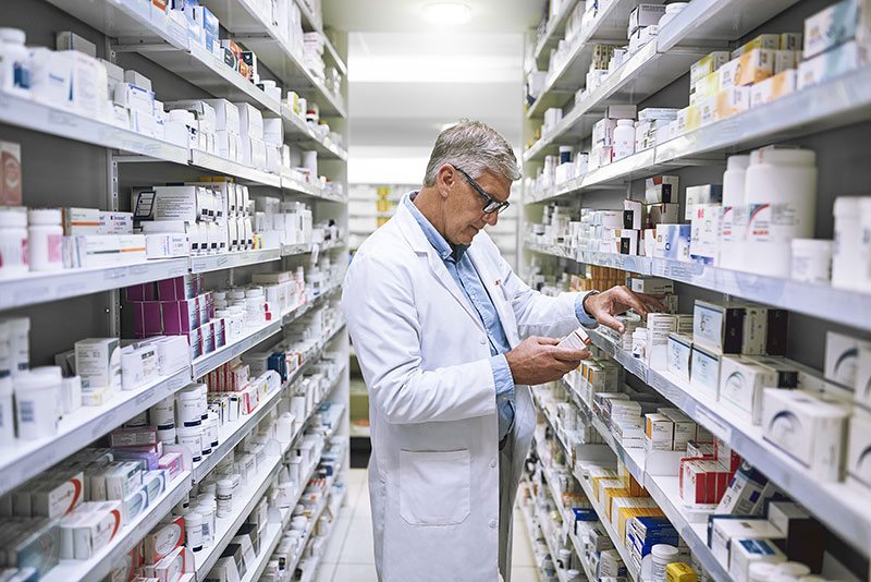 Experienced pharmacist looking at a shelf of medications